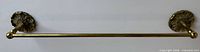 Full view of brass towel bar showing both floral rosette mounts and straight bar