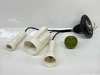 Three white ceramic flashlight-shaped shades with black canopy and apple for scale