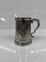 Front of pewter tankard with crest and engravings visible