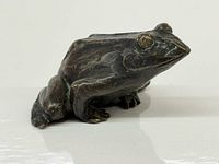 Front angled view of bronze frog showing facial detail and patina