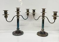 Both matching three-arm silver plated candelabras side by side