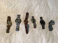 All five watches laid out on quilted surface