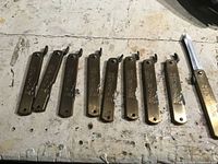 Nine brass folding knives lined up closed