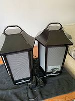 Two hexagonal Bluetooth speakers with handles, power adapter and cable visible