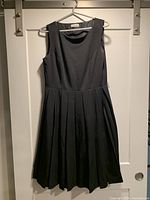 Front view of black Calvin Klein sleeveless dress showing pleated skirt and bodice