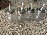 Four owl-designed glass jars with lids and straws arranged on table