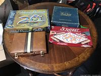 All four games on table: two Trivial Pursuit boxes, Scrabble box, closed backgammon case