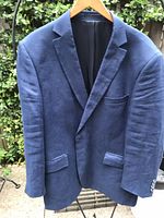 Front view of navy linen blazer on hanger showing lapel and pockets