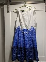 Front view of sleeveless white and blue Jones New York dress hanging on hanger