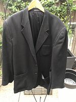 Front view of black wool blazer on hanger showing buttons, lapel and patch pockets