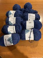 Ten blue skeins Loops & Threads yarn on table