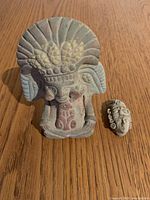 Front view of seated deity figure and small face mask