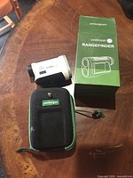 UnderPar rangefinder, case, strap and box displayed on tabletop