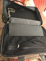 Bag open showing black patterned interior, mesh zip pocket, laptop sleeve and straps