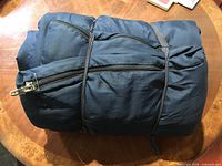 Sleeping bag folded and tied, showing exterior fabric, zipper, tie straps