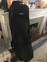 Front view of black wheeled golf travel bag standing upright