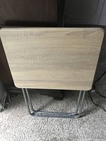 Front view of folded tray table showing wood-grain top