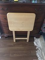 Front view of folded wood TV tray in front of dresser