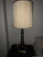 Full view of brass table lamp with cream shade