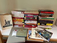All items laid out: stacks of books, Joy of Cooking standing, Honour book and DVD foreground