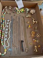 Overview of entire lot in tray showing necklaces, brooches and pins