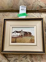Framed farmhouse painting resting on patterned upholstery