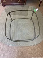 Top view of square glass table showing glass surface, beveled edge, metal frame outline