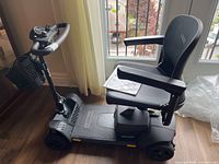 Side view of Go-Go Ultra X scooter with seat, armrests, basket and manual on seat