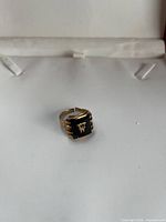 Front view of gold-tone ring with black inlay and ‘W’ monogram