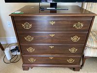 Front view showing four brass-handled faces, bottom real drawer, top three forming hinged door