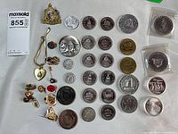 Entire lot laid out showing coins, tokens, pins, brooch and pendant