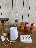 Group shot of both oil lamps, two lamp oil bottles, electric diffuser with cord, essential oil set box and reed diffuser package