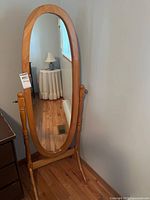 Front view of oval mirror on wooden cheval stand