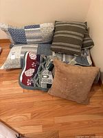 Stack of quilt, green striped pillows, tan pillow and throw blanket