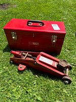 Closed red toolbox beside hydraulic floor jack