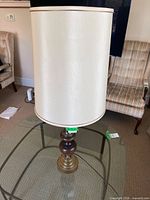 Full view of lamp with shade on glass table