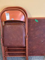 stacked two folding chairs and folded tabletop leaning against wall