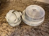 Stacked teacups on saucers beside two plate stacks