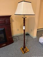 Full view of floor lamp showing wood column, base and shade