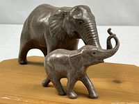 Front left view of ceramic mother and calf elephant figurines on wood plaque
