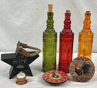 Group shot of three colored bottles, two rooster clocks, metal star lantern and LED tea light