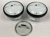 Top view showing two Nordic Ware cookers with lids and separate Calphalon glass lid