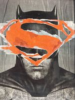 Close view of Batman face with orange Superman logo overlay