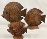 Three carved wooden fish sculptures grouped