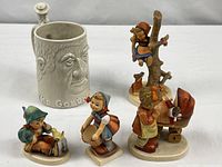 Group shot: four Goebel Hummel figurines and Fitz & Floyd mug