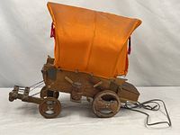 Full view of wooden covered wagon lamp with orange canopy and power cord