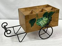 Full view of caddy on wrought-iron carriage frame showing grape motif and wheels