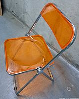 Full view of orange acrylic folding chair, unfolded
