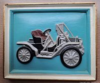 Front view of chalkware wall plaque with antique car relief