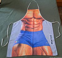 Full view of apron showing bodybuilder print, shorts, straps and MACHO text